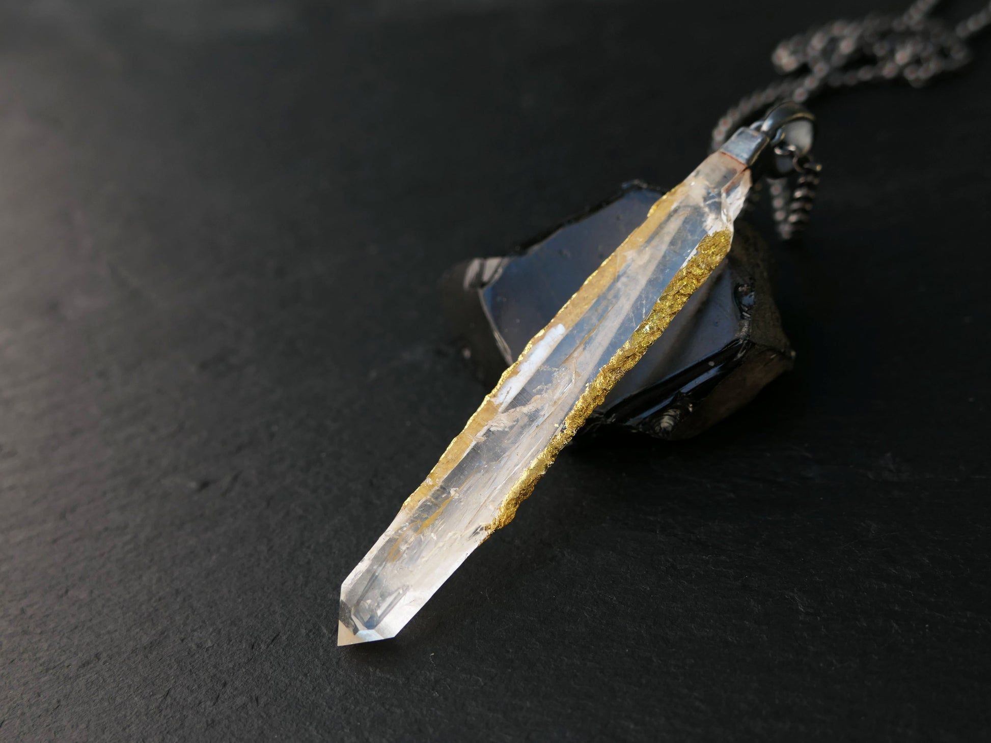 Quartz crystal pendant with 24k gold leaf set in black sterling silver on a chain.