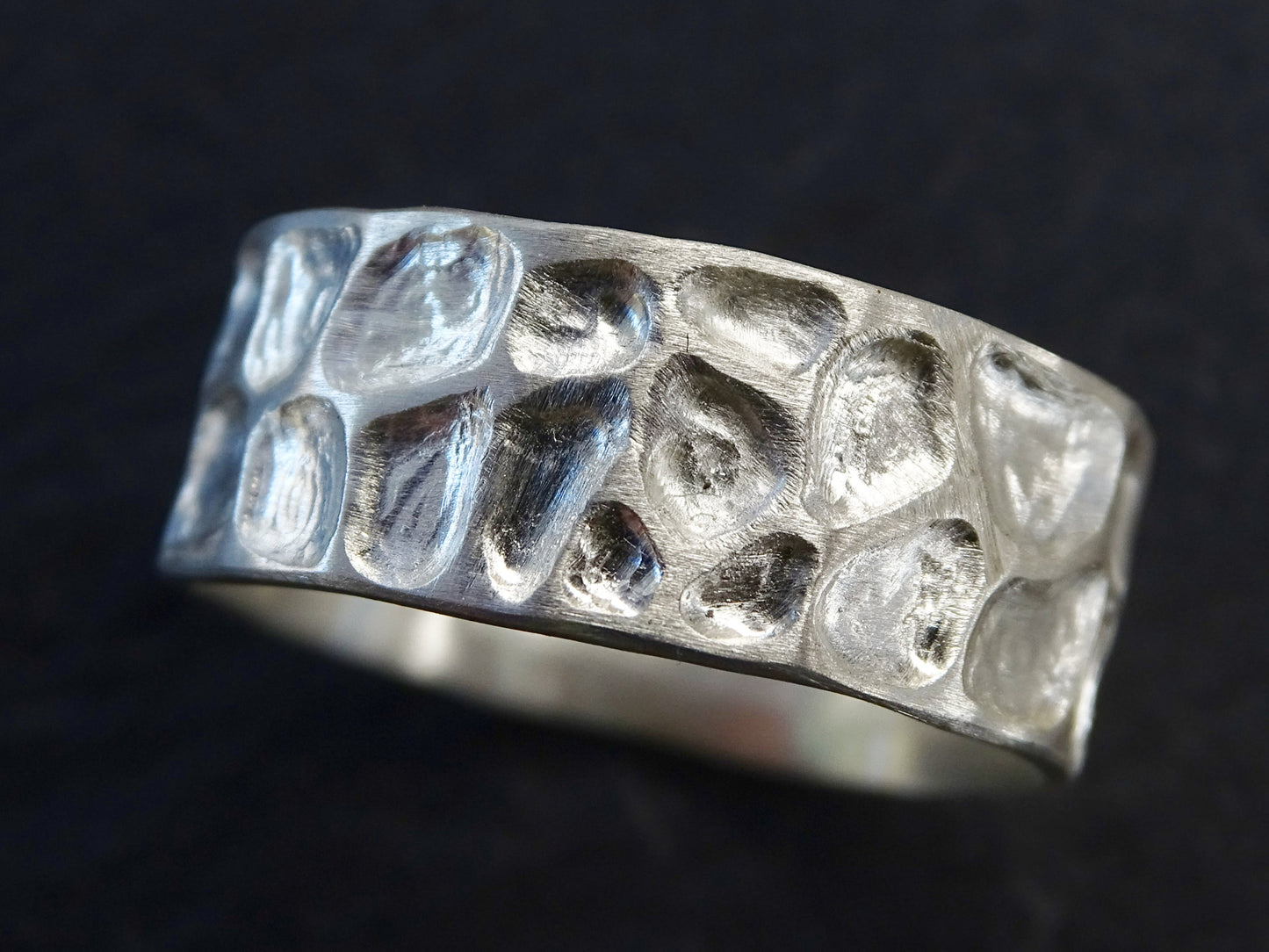 Handmade sterling silver men's wedding ring with carved dragon skin texture resembling lizard skin or pebbles, 8mm wide, customizable size and finish.