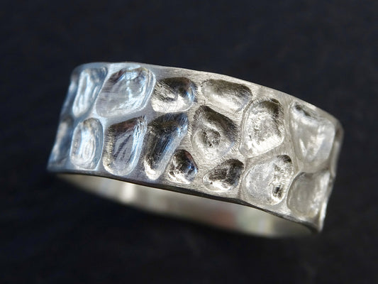 Handmade sterling silver men's wedding ring with carved dragon skin texture resembling lizard skin or pebbles, 8mm wide, customizable size and finish.