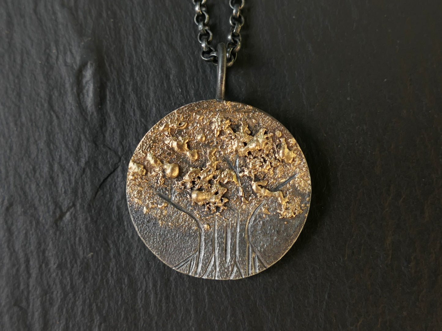 Hand engraved tree of life pendant in darkened silver with molten 14k gold details on black chain