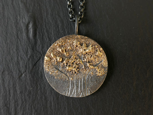 Hand engraved tree of life pendant in darkened silver with molten 14k gold details on black chain