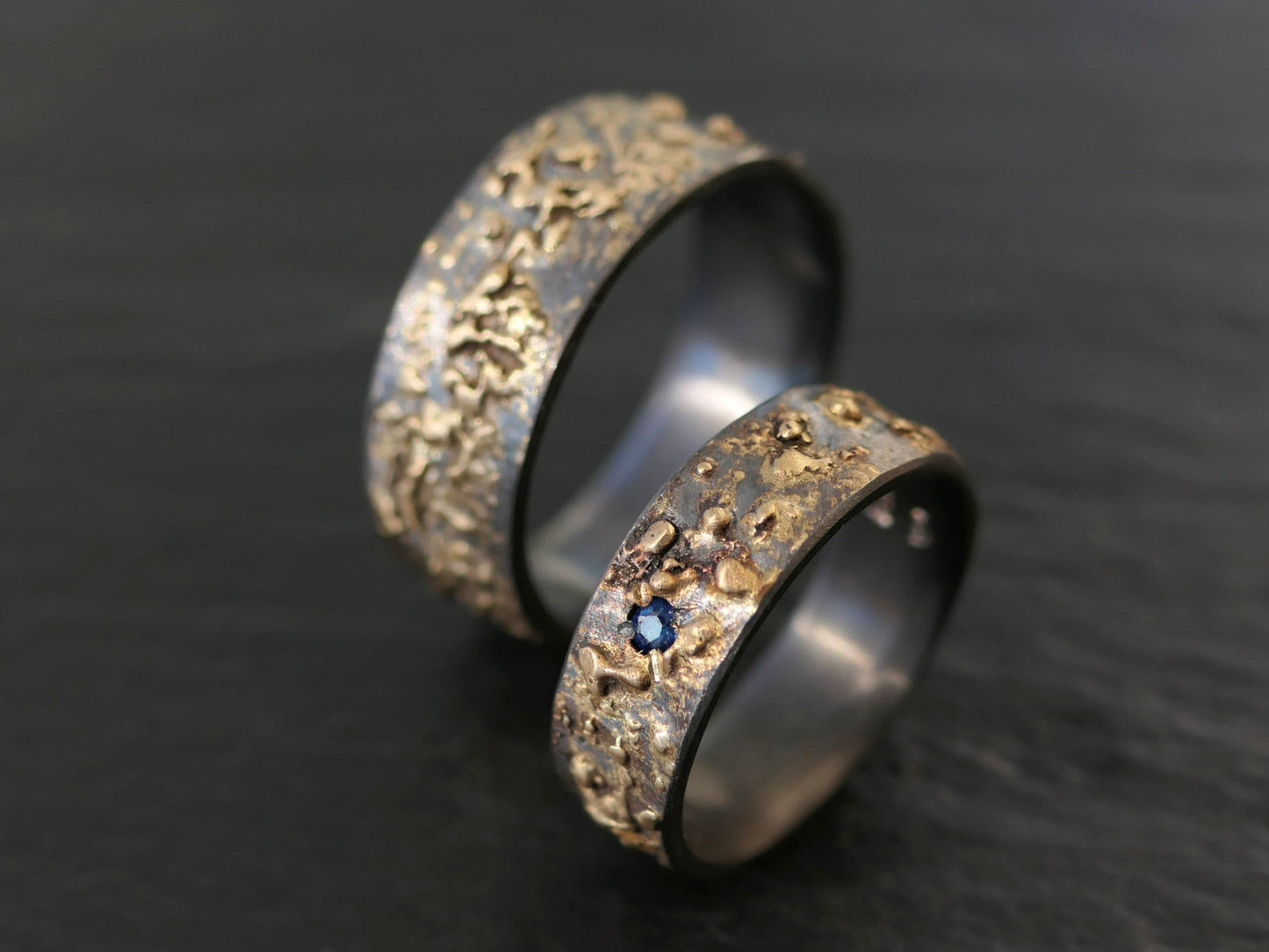 gold and black silver wedding ring set with blue sapphire gemstone and textured fire-forged surface