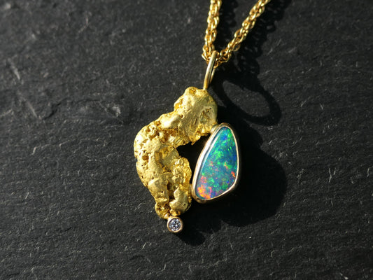Boulder opal and gold nugget pendant with diamond accent on black background.
