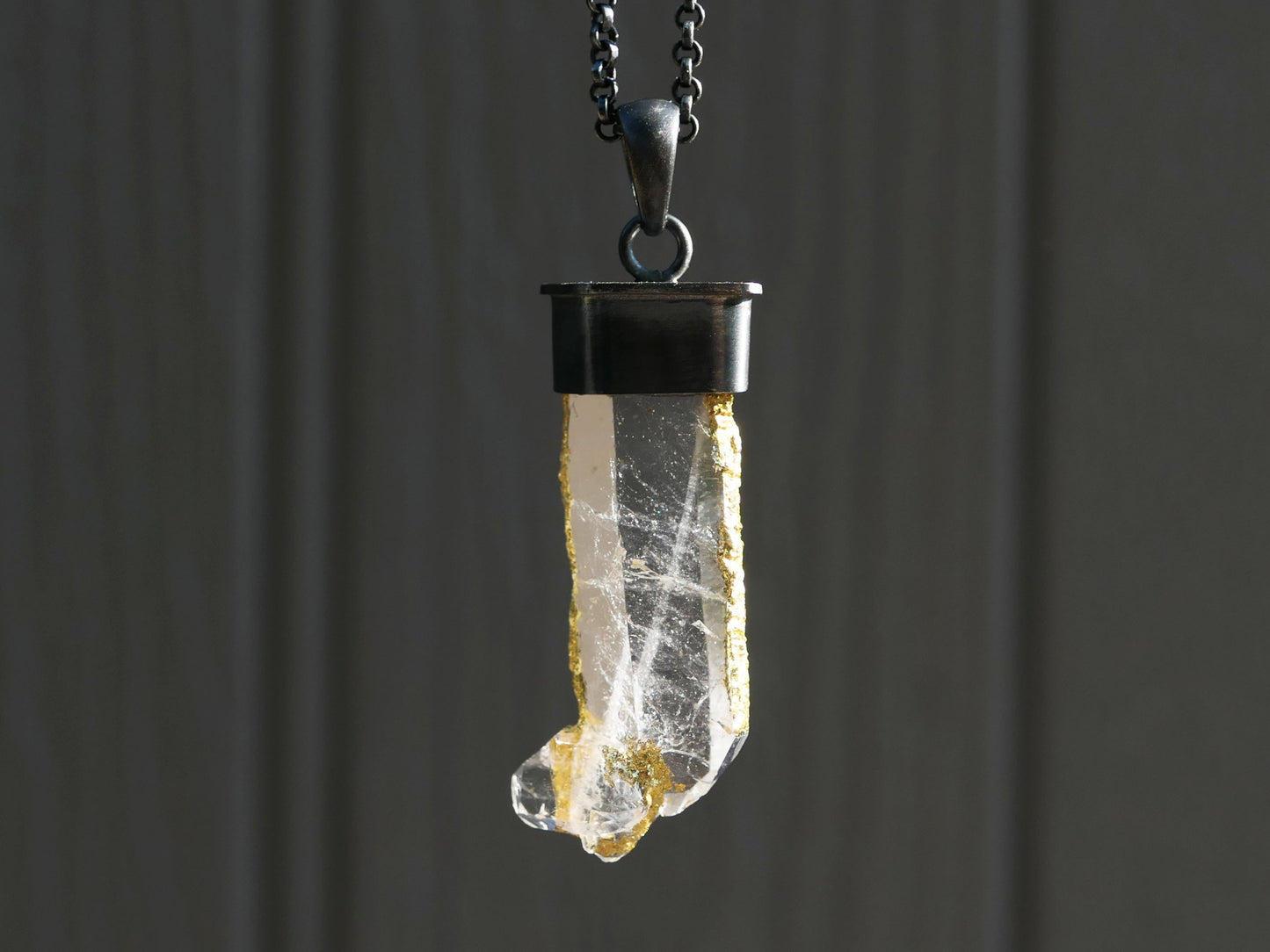 Clear quartz crystal necklace with natural gold leaf accents set in black oxidized sterling silver