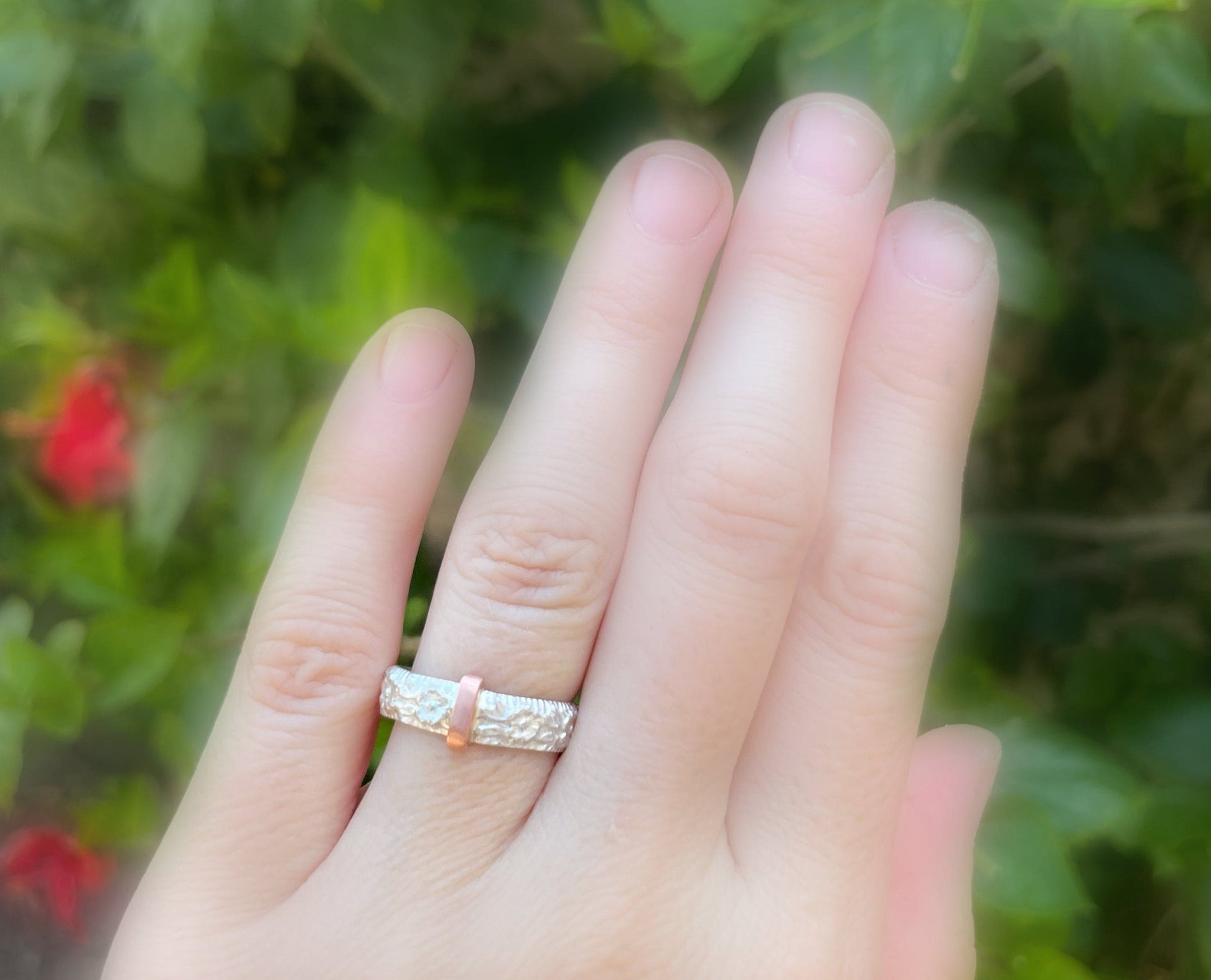 Sterling silver Scottish sporran band wedding ring with copper centerpiece displayed on hand.