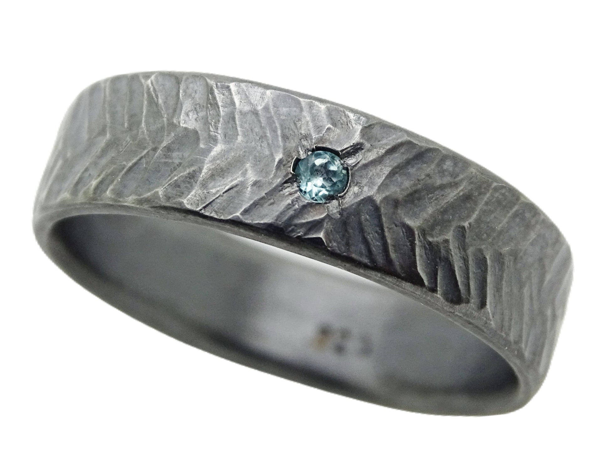 darkened silver herringbone ring with small blue topaz gemstone and hammered chevron pattern