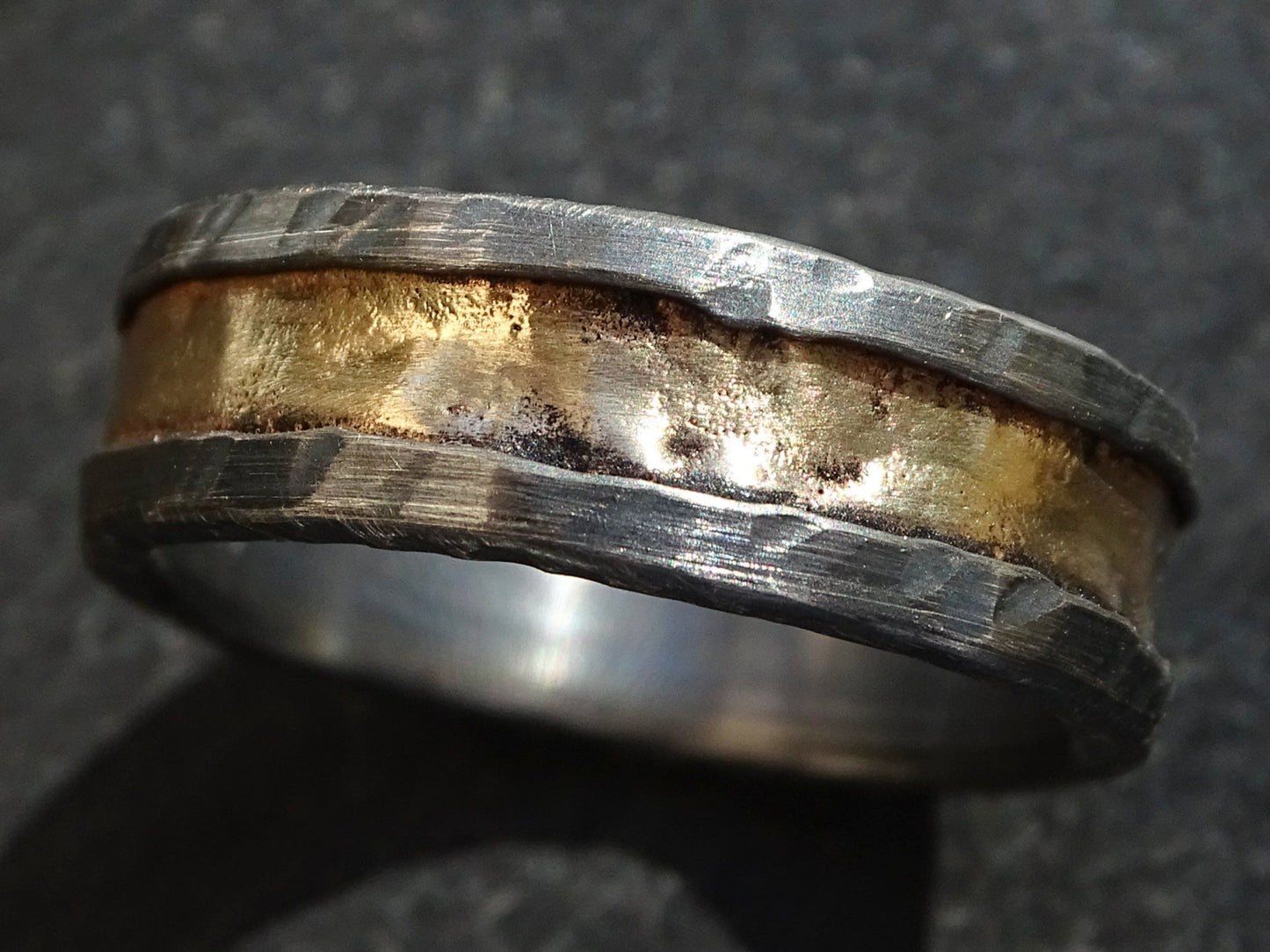 black sterling silver viking ring with molten 14k yellow gold center and hammered textured edges