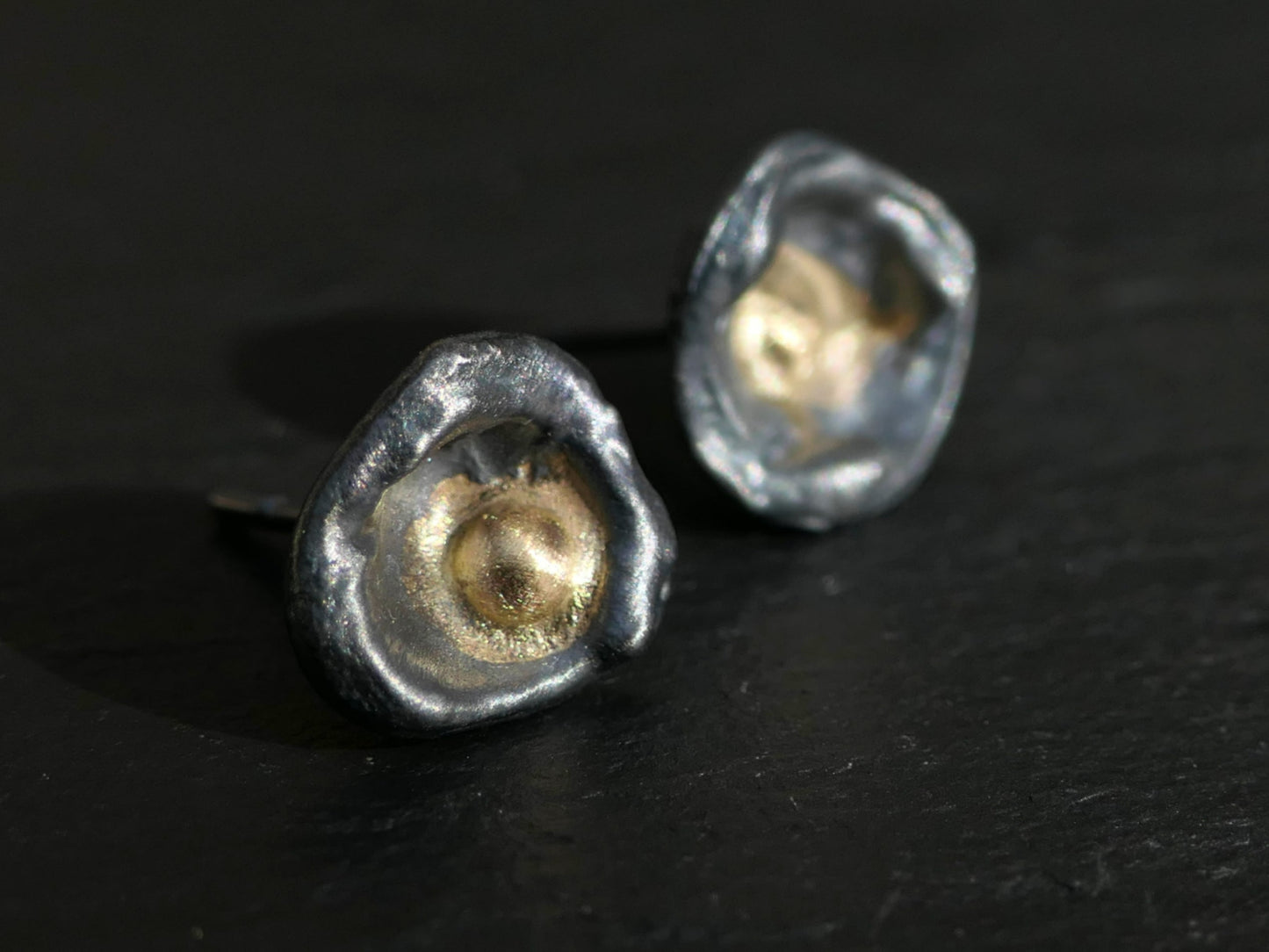 Handmade water cast sterling silver stud earrings with solid 14k gold centers, minimalist dished design.