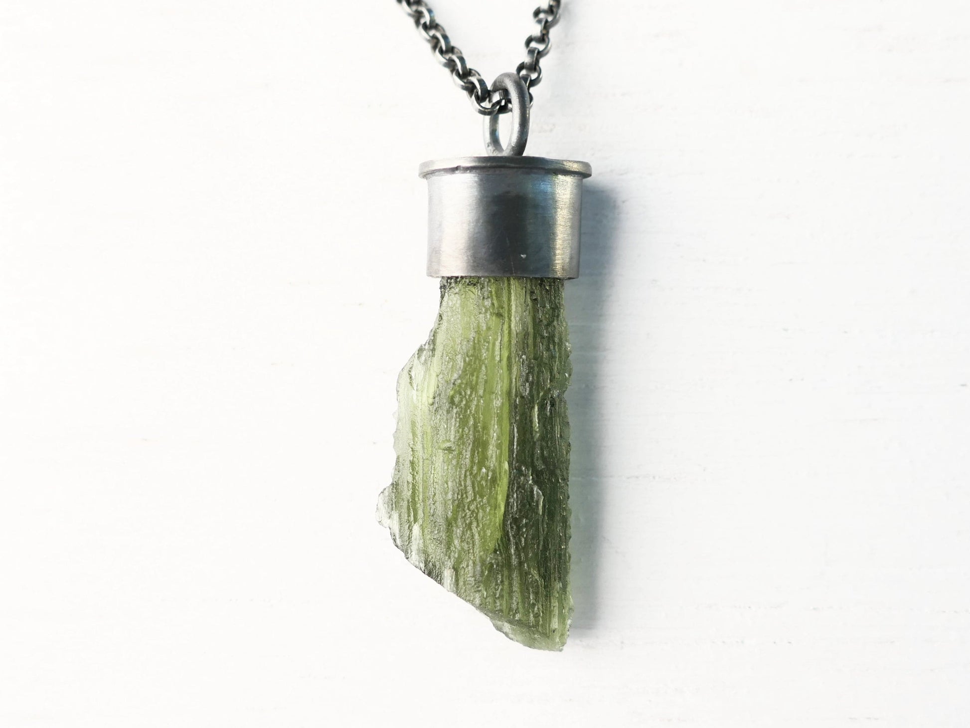 Raw green moldavite pendant in darkened black sterling silver setting on chain