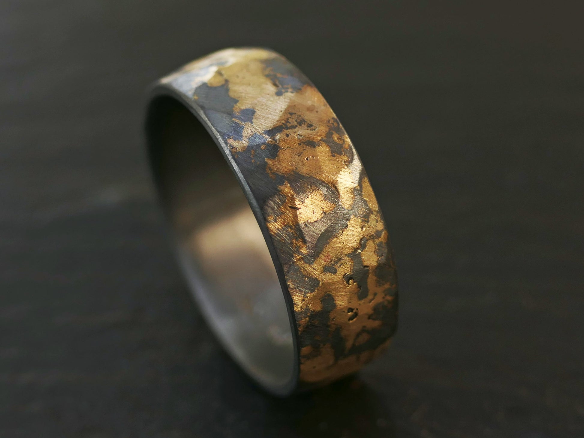 forged men's wedding band in gold and dark silver with hammered texture
