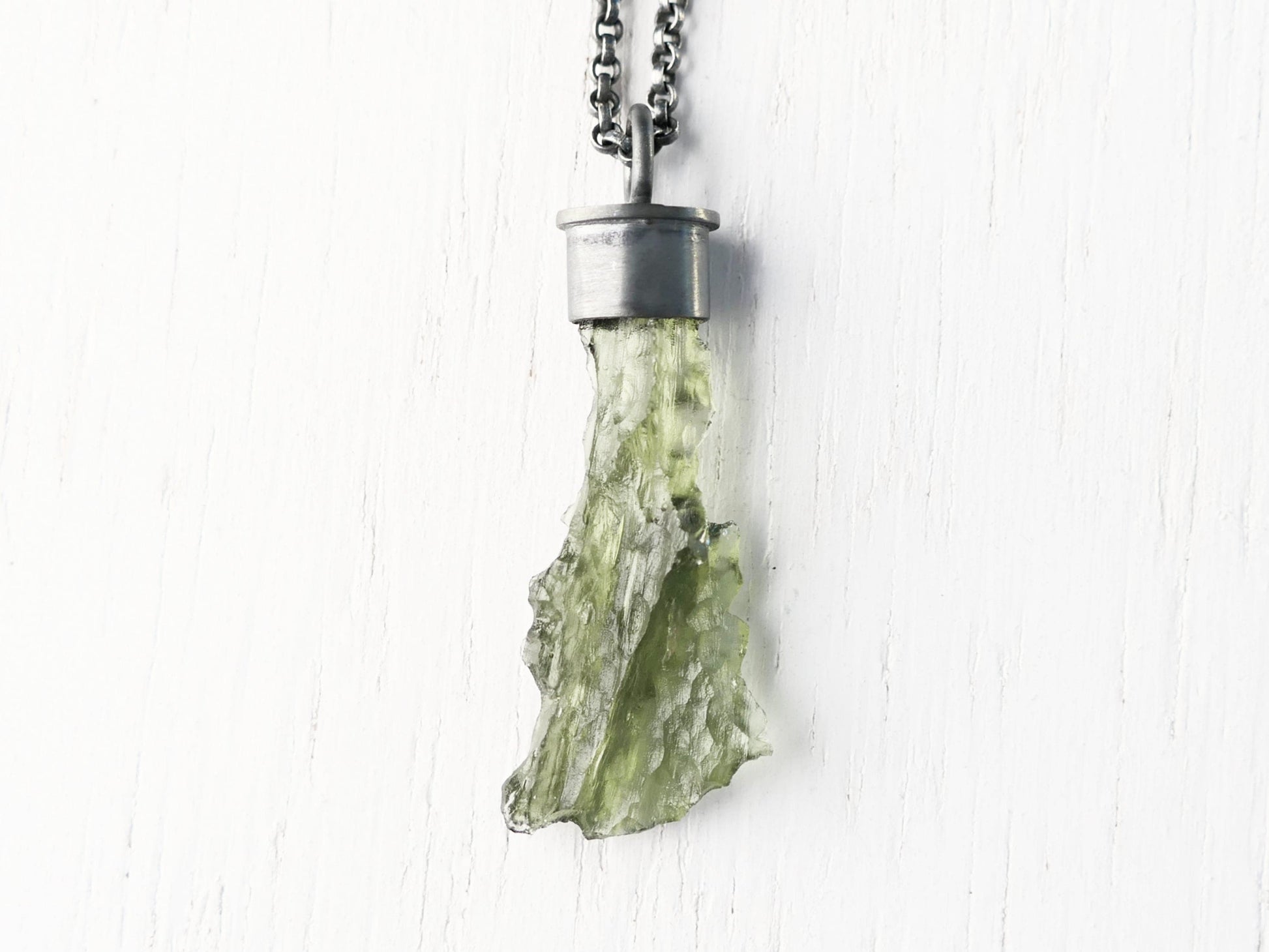 Uncut green moldavite crystal pendant in black sterling silver setting on chain