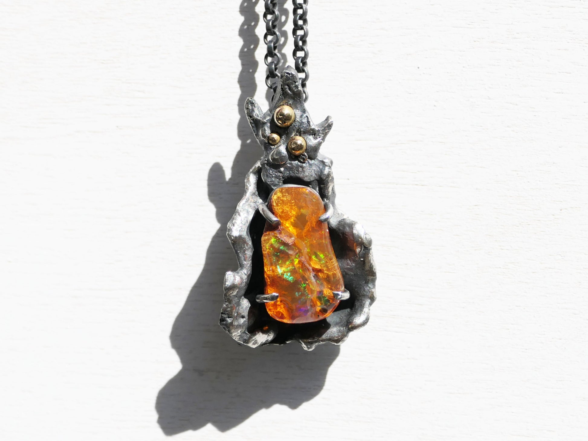 Handmade fire opal pendant with darkened sterling silver and 14k gold accents, featuring a vibrant Mexican fire opal gemstone.