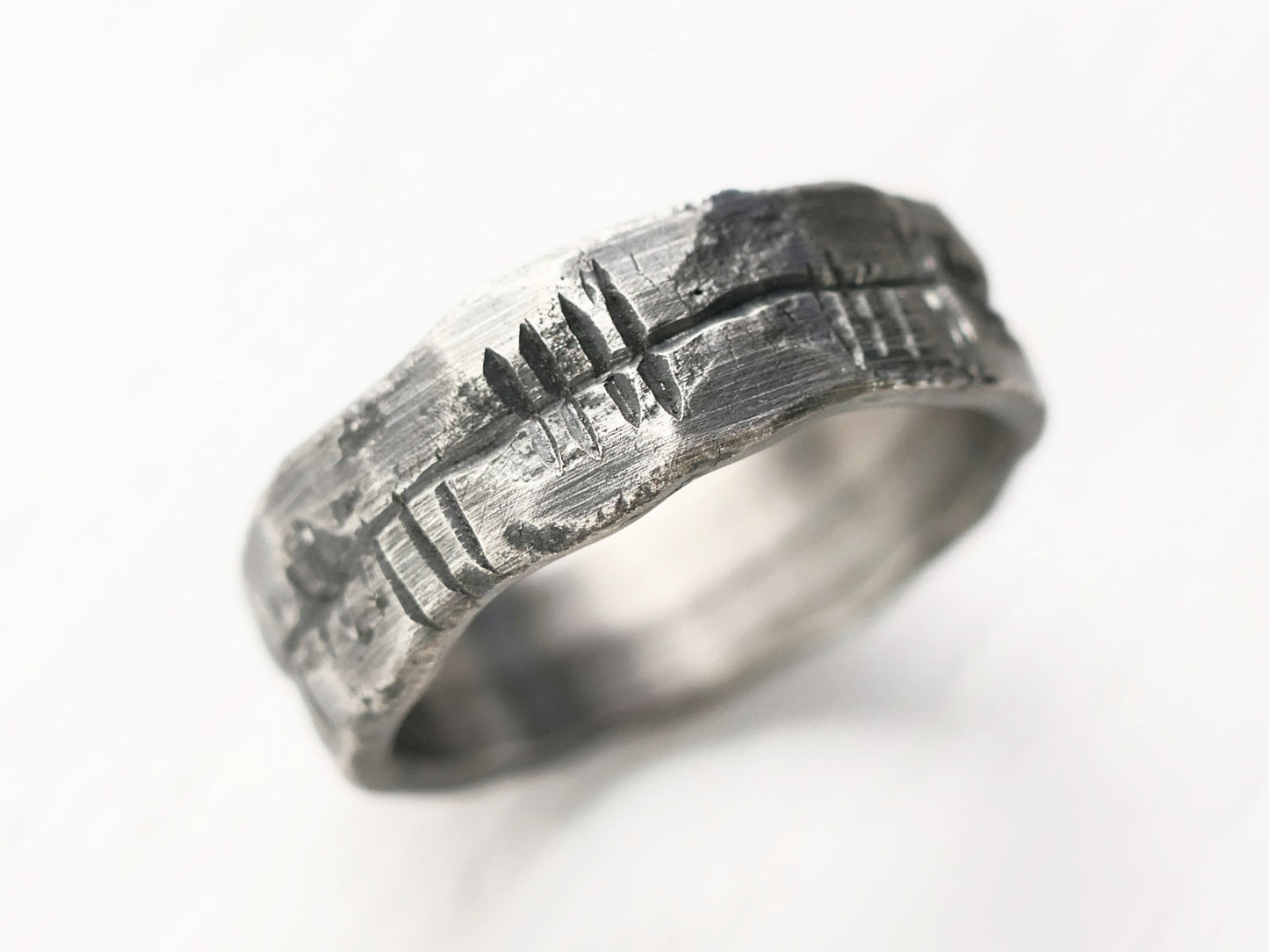 Dark oxidized handmade sterling silver Ogham ring with rustic engraved script and textured finish