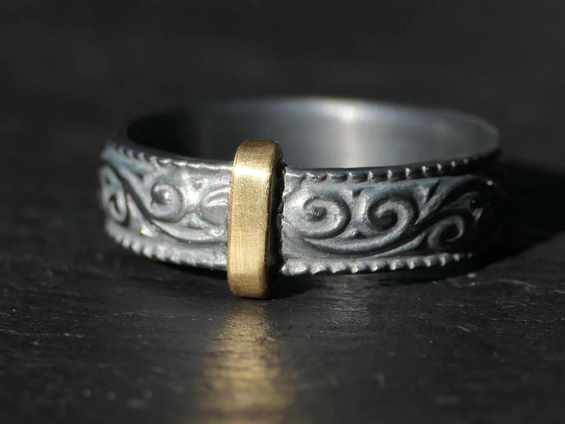 Mixed metal Scottish wedding ring with scroll pattern and bronze center on oxidized sterling silver band