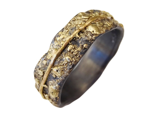 Black oxidized sterling silver men's wedding band with textured surface and fused 14k yellow gold accent band