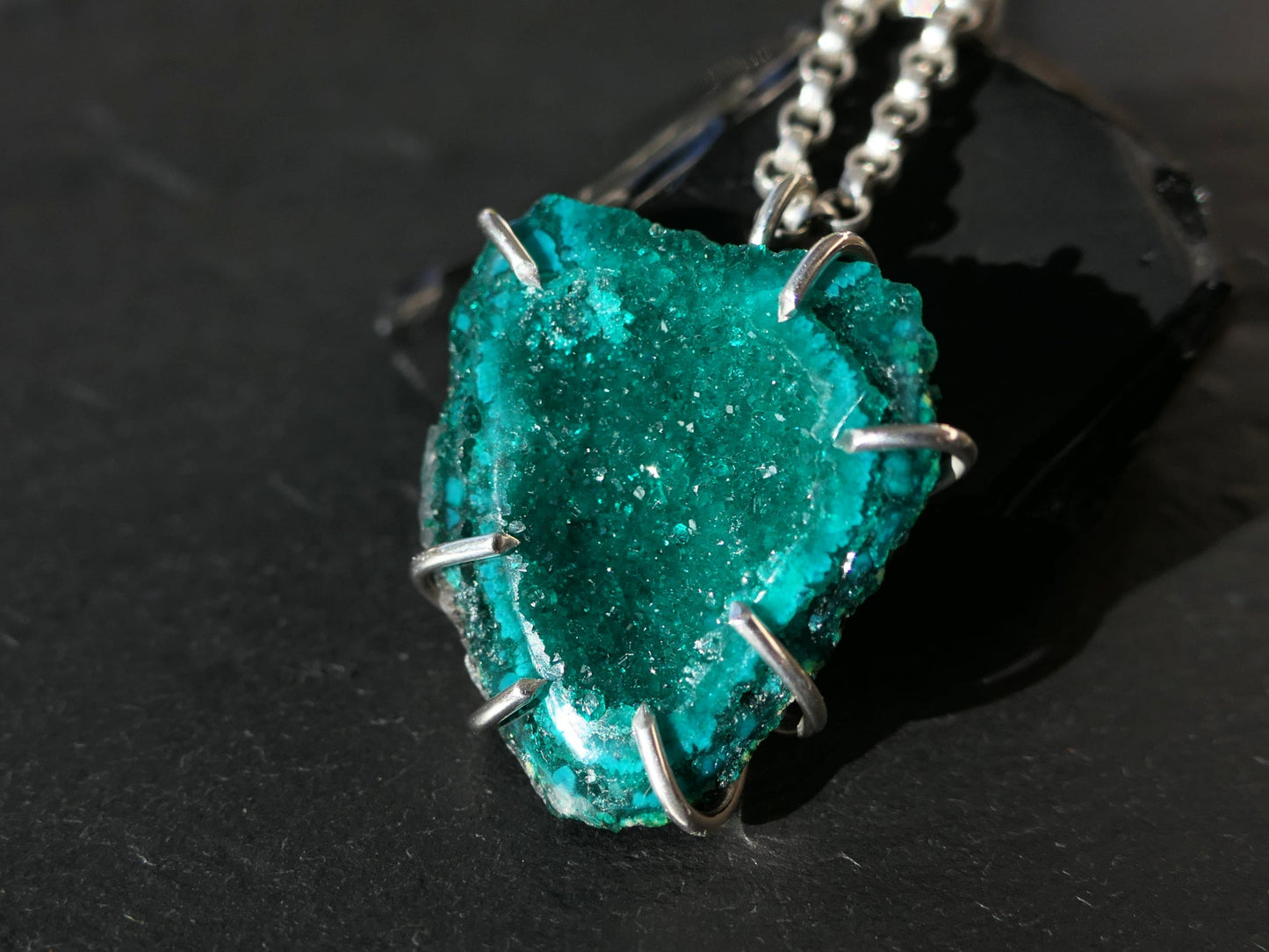 Raw dioptase crystal necklace pendant in sterling silver setting.