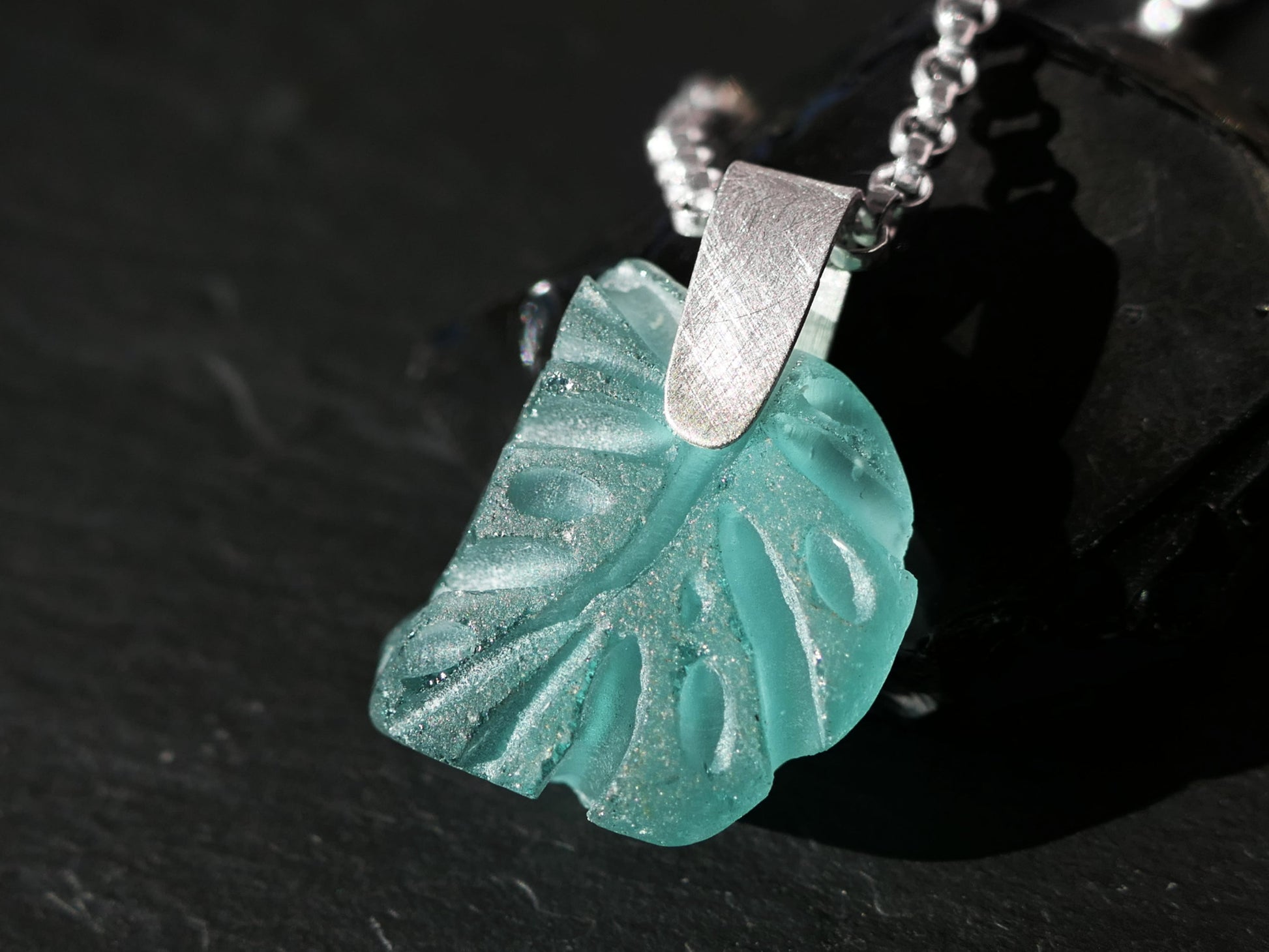 Aqua carved sea glass pendant in Monstera leaf shape with sterling silver bail and chain