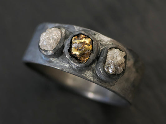 Dark oxidized sterling silver ring with central raw gold nugget and two rough grey diamonds gold nugget ring