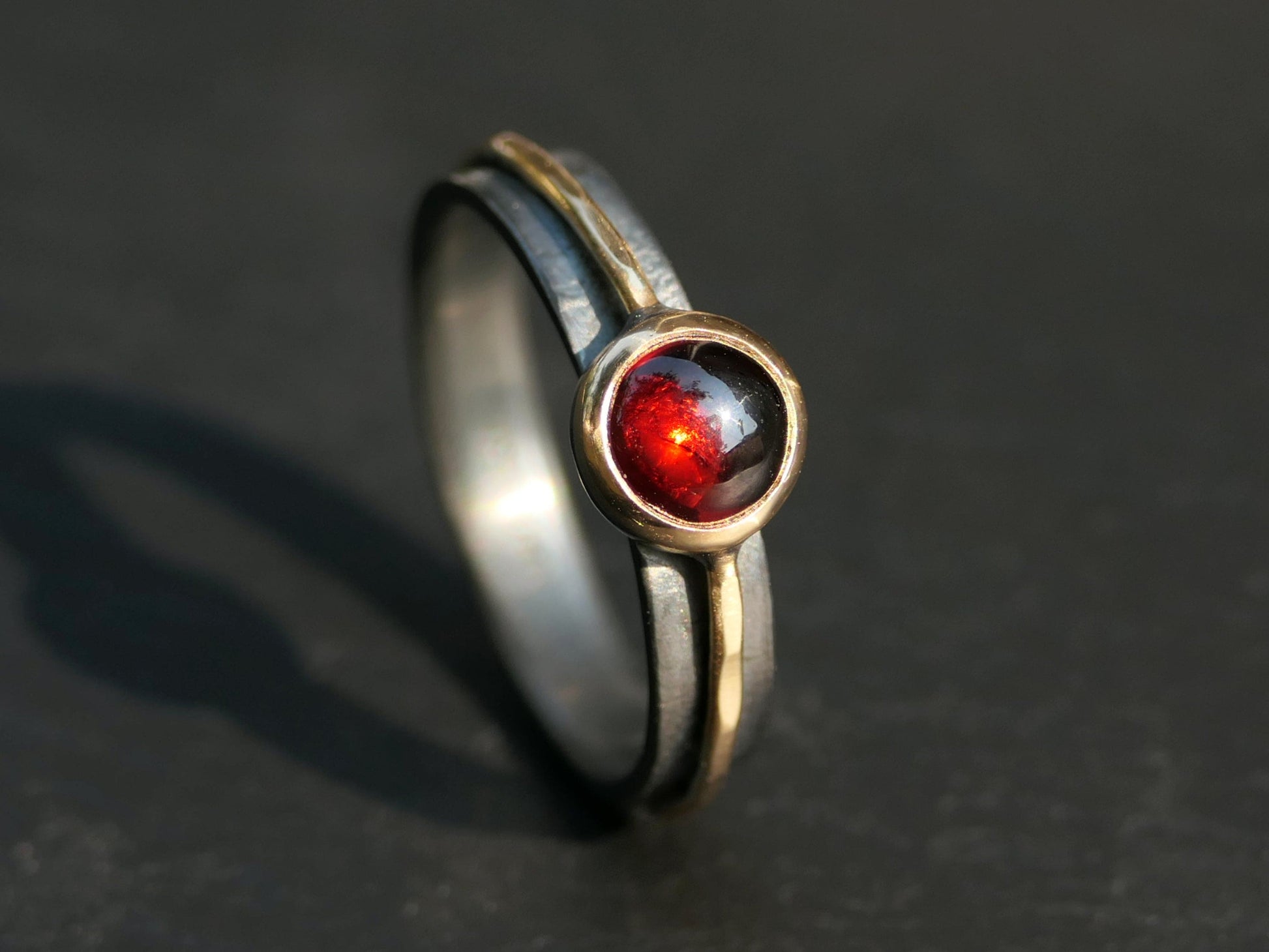 Viking style garnet ring with blood red cabochon set in 14k gold bezel and black sterling silver band