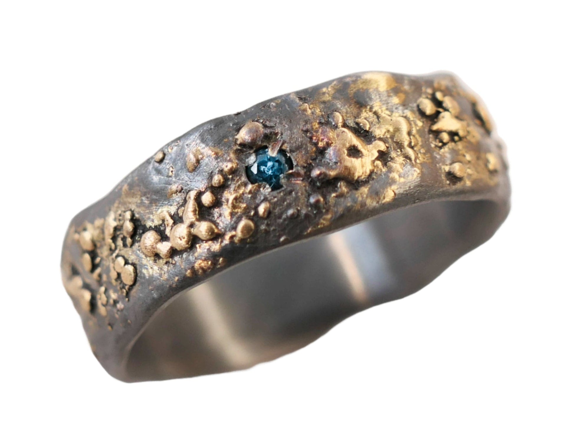 unique men's engagement ring in dark silver and gold with small blue gemstone and molten textured band