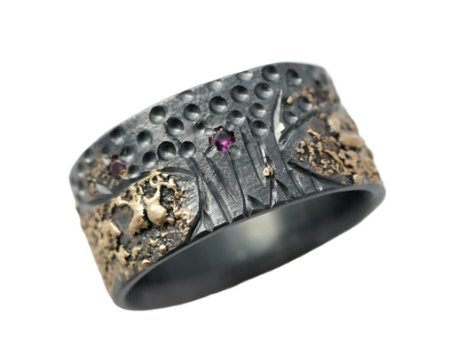 Men's ruby wedding ring with unique tree of life design in black and gold tones, featuring small red rubies and hand-engraved details