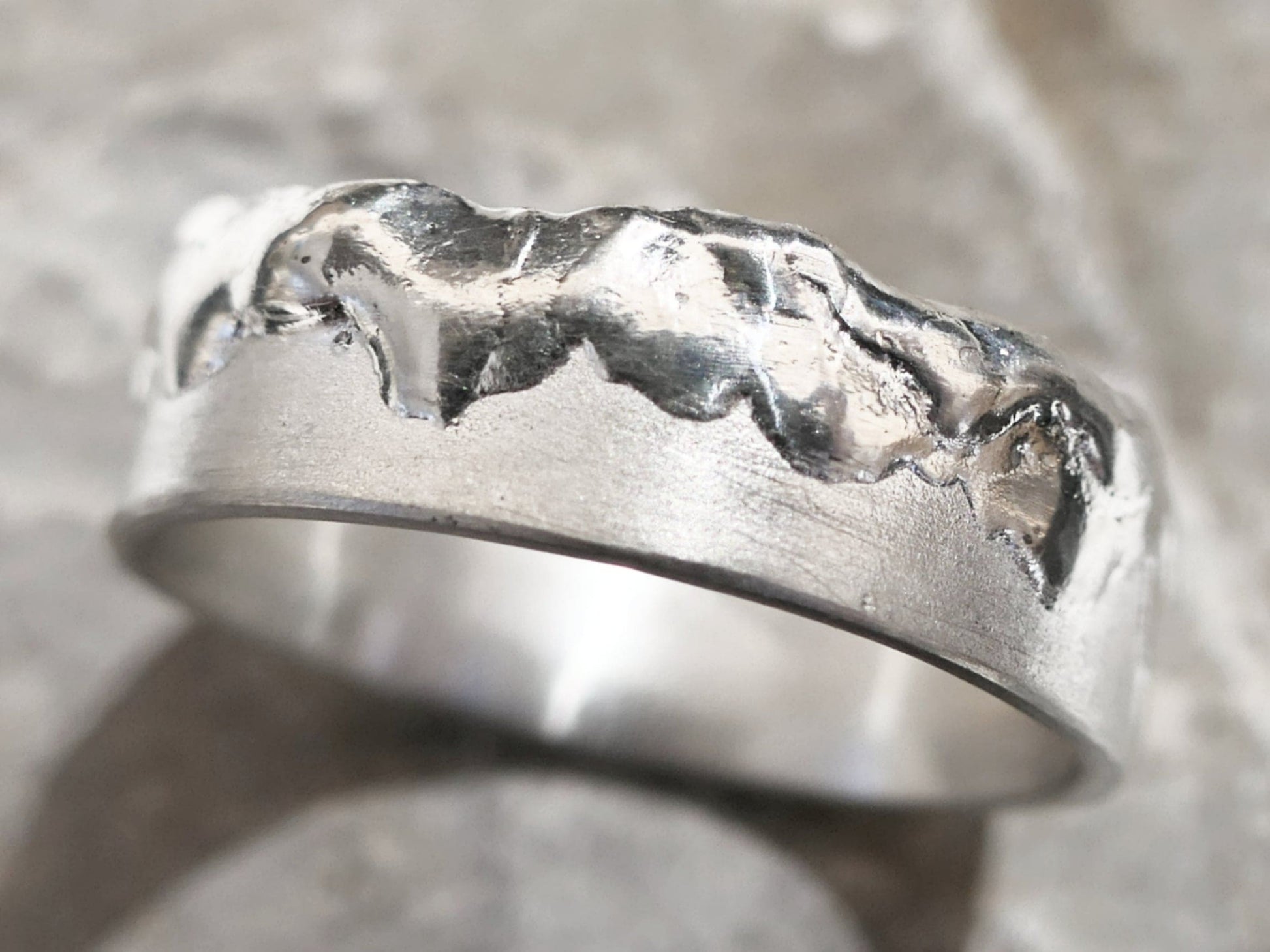 close-up of cool mens ring handcrafted from fine silver with partially molten textured surface and uneven edge
