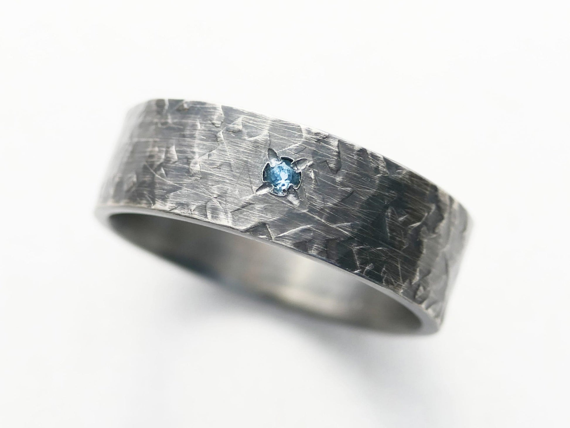Men's oxidized silver wedding band with small gemstone.