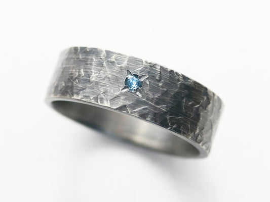 Men's oxidized silver wedding band with small gemstone.