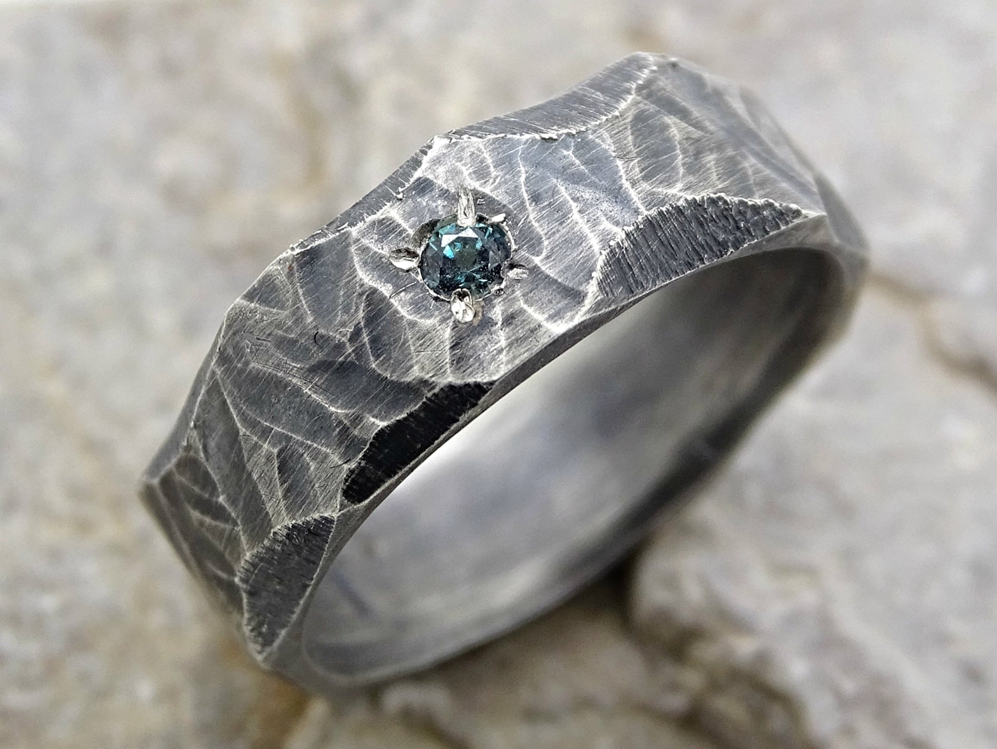 hand forged rustic silver ring with textured band and small dark blue gemstone