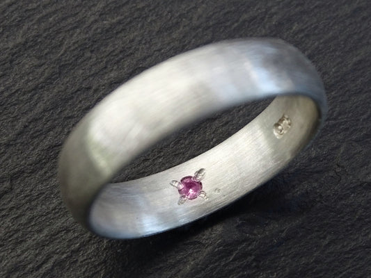 Sterling silver domed ring with a hidden pink gemstone set inside the band