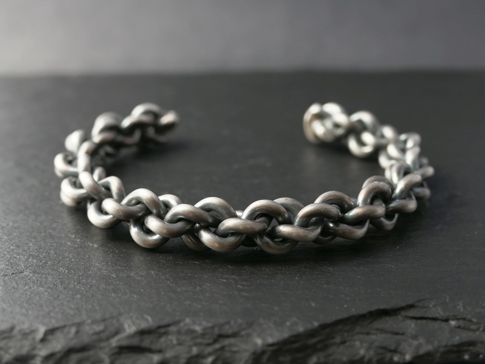 woven sterling silver chain bracelet with braid design and oxidized finish on dark slate surface