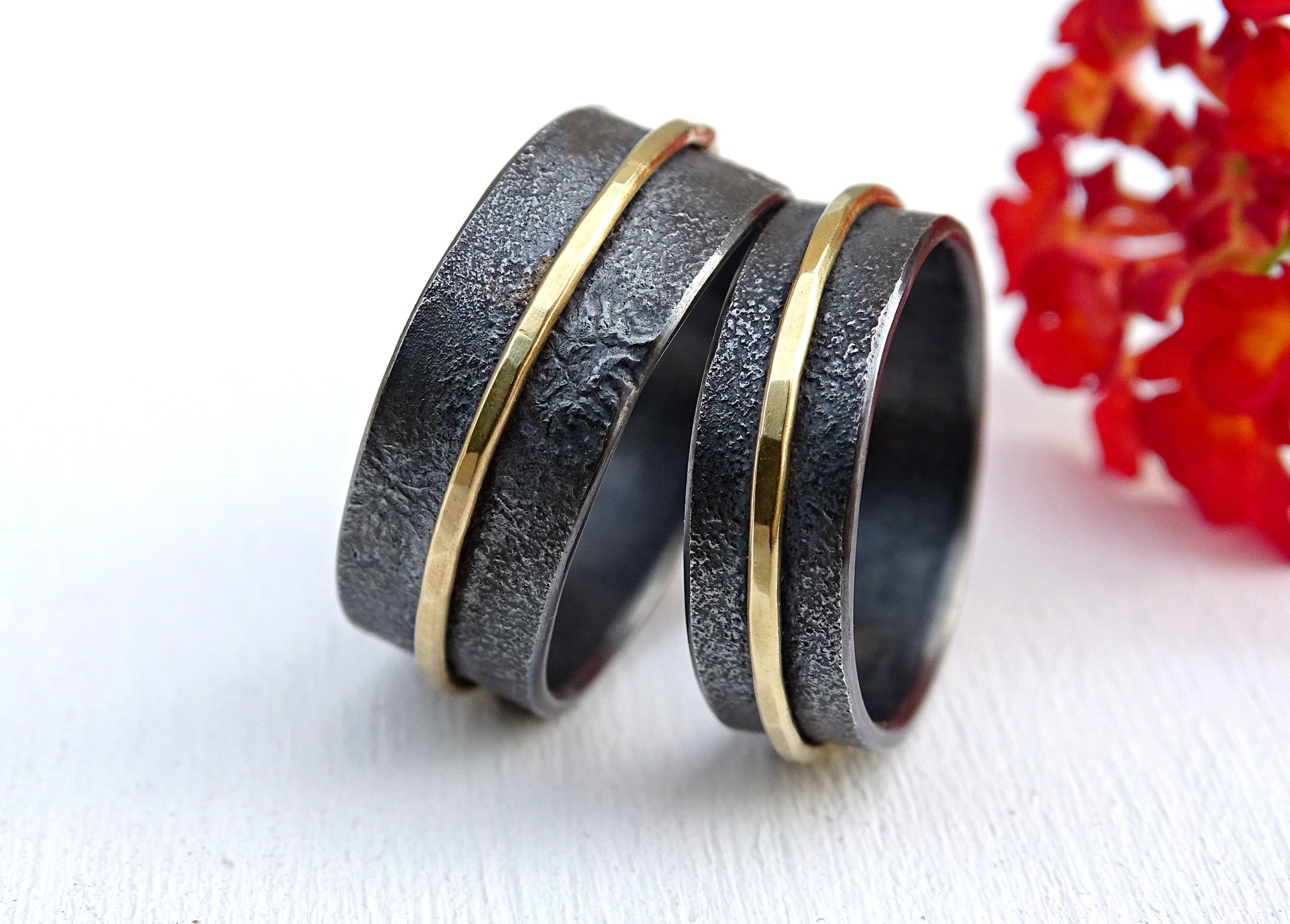 Black silver and 18k gold matching wedding ring set with textured surfaces and gold accent bands.