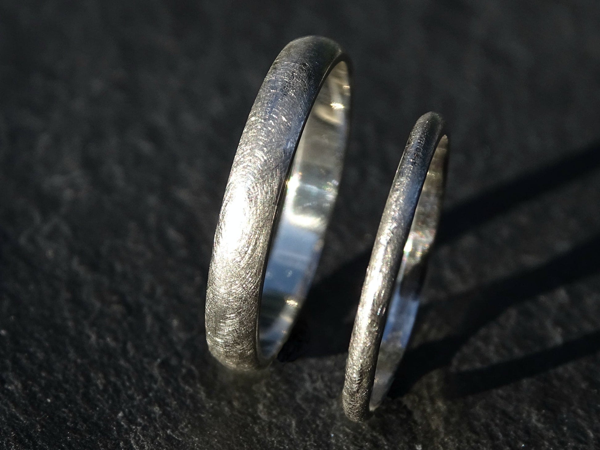 Domed platinum wedding ring set with slim matching bands in matte finish on dark background