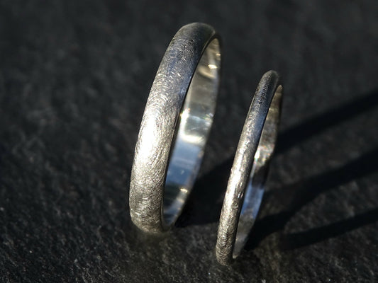 Domed platinum wedding ring set with slim matching bands in matte finish on dark background