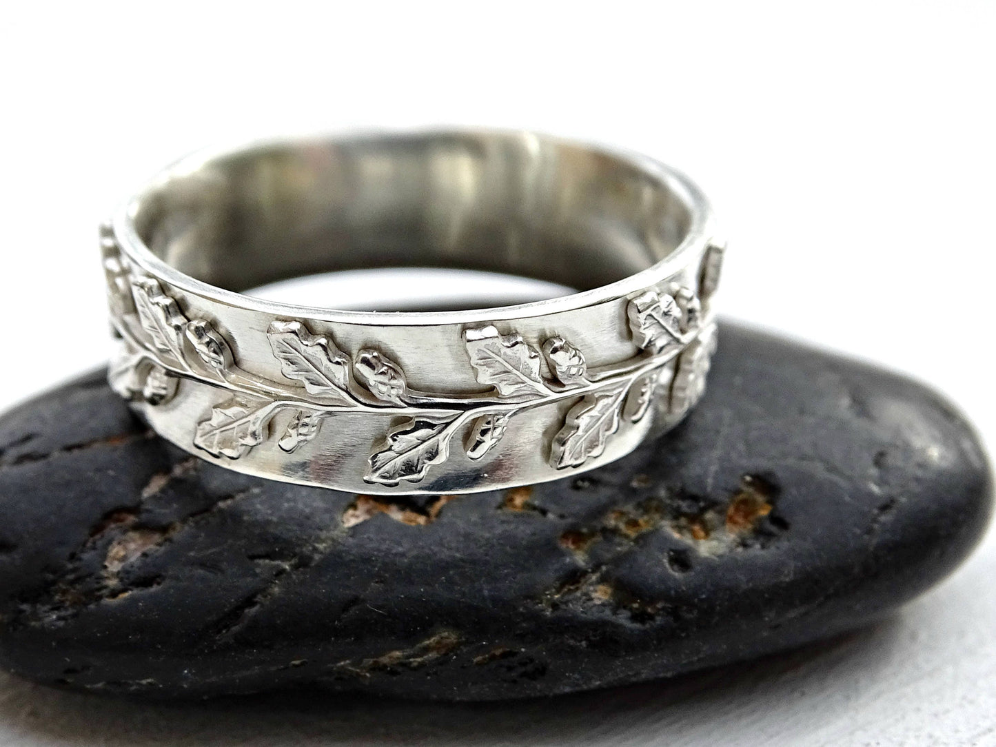 Sterling silver leaf engagement ring with oak leaf design on 6mm wide band placed on a dark stone.