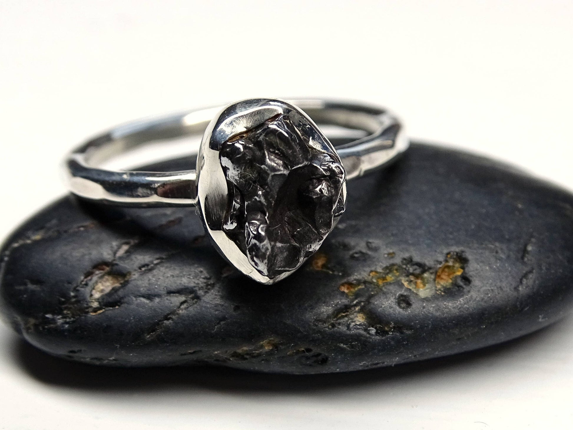 silver meteorite ring with genuine iron nugget and hammered sterling silver band on black stone
