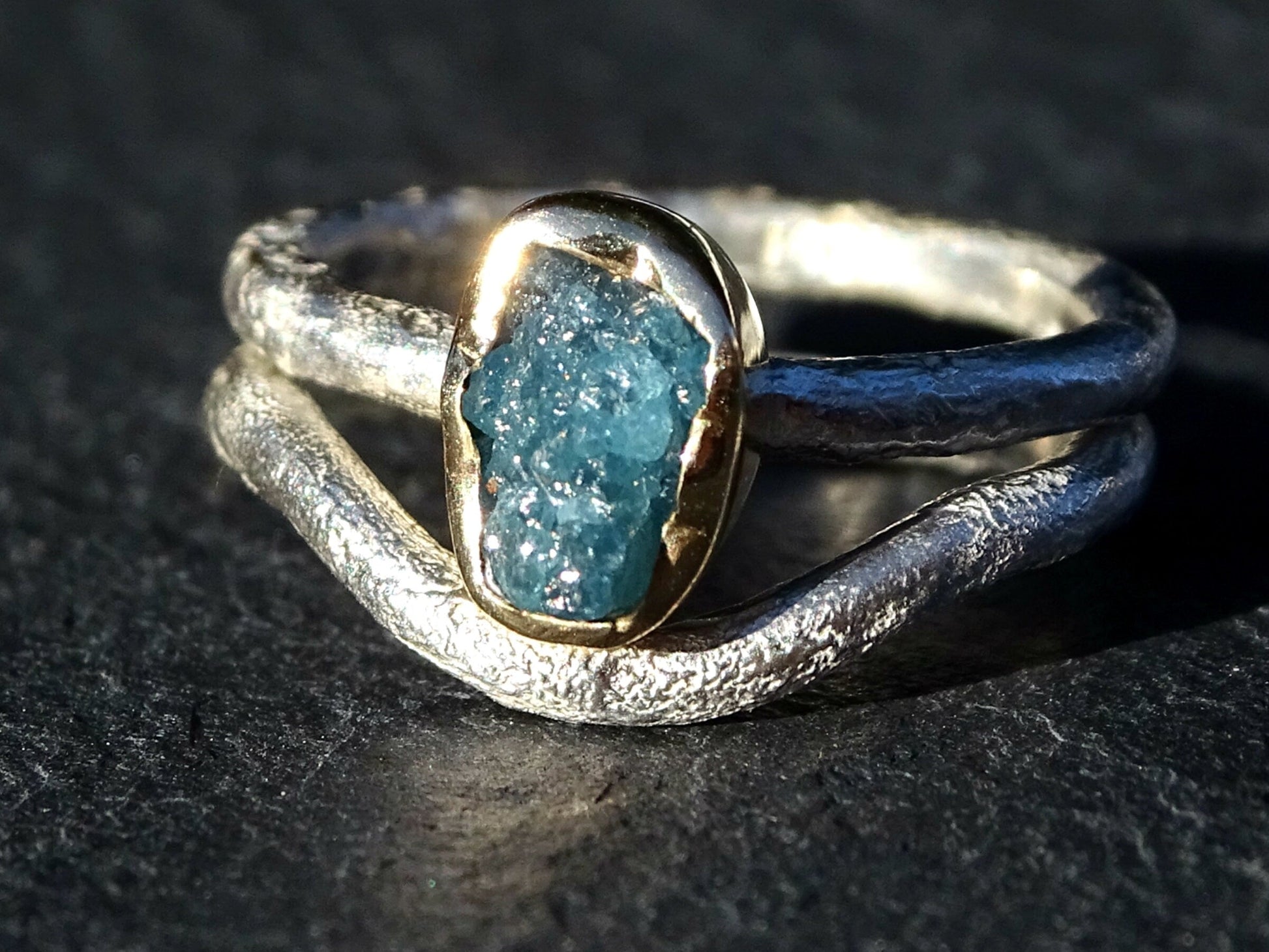 Raw blue diamond ring with gold bezel and textured silver band, unique engagement ring design