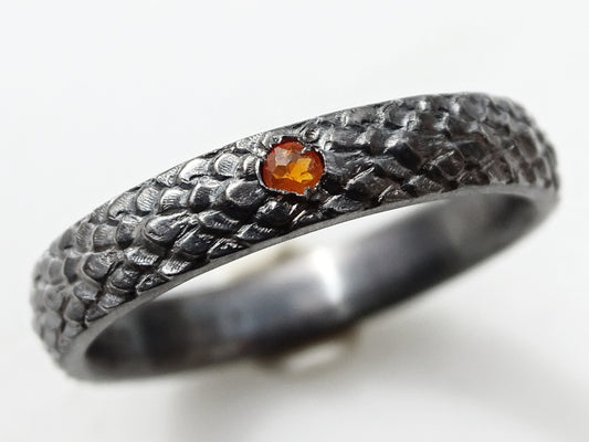 Dark silver dragon scale ring with small orange gemstone set in black oxidized sterling silver band
