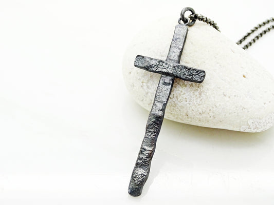 Rustic black oxidized sterling silver cross necklace with molten texture and long pendant design.