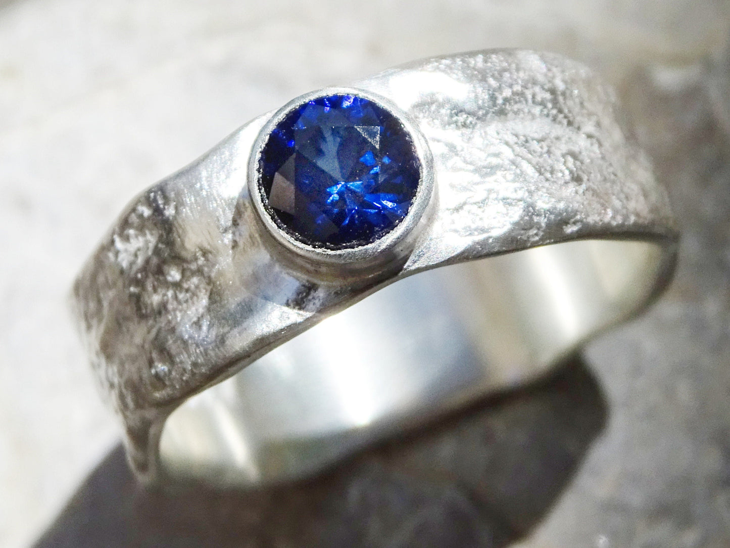 Men's sapphire wedding band with molten sterling silver and bezel-set blue sapphire gemstone