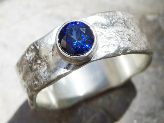 Men's sapphire wedding band with molten sterling silver and bezel-set blue sapphire gemstone