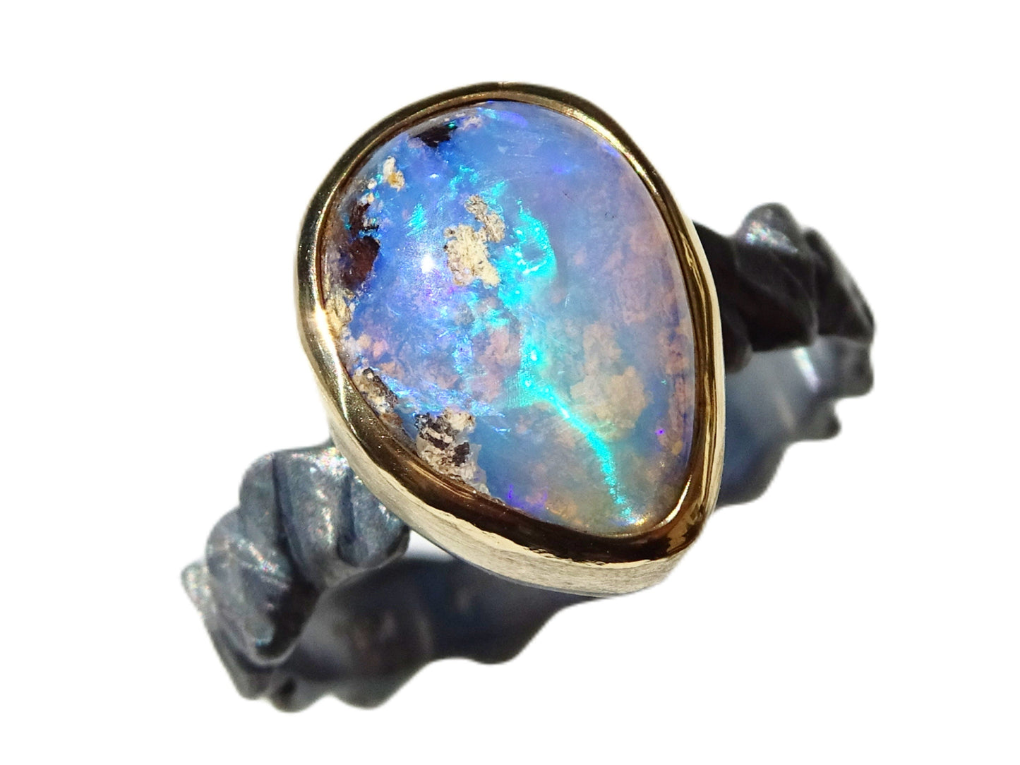 Electric blue and green Boulder opal ring set in 14k gold bezel with hand-carved black sterling silver band.