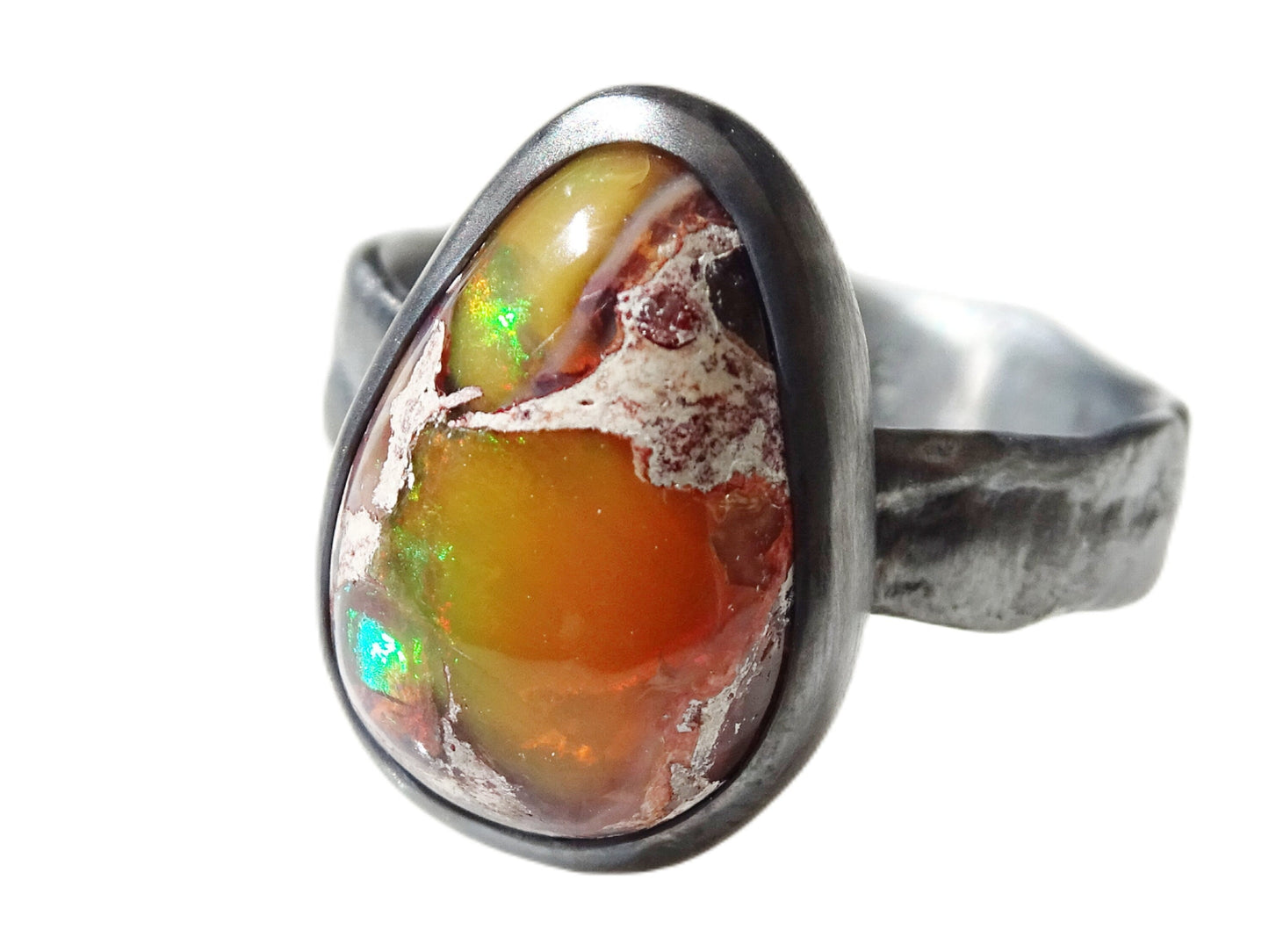 dark silver fire opal ring with organic drop-shaped Mexican fire opal showing green, red, and orange flashes in a closed bezel setting