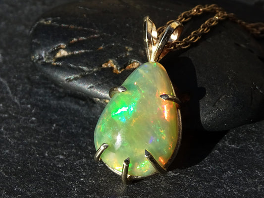 14k gold opal necklace with a teardrop-shaped rainbow welo opal pendant showing vibrant green, orange, and blue hues.
