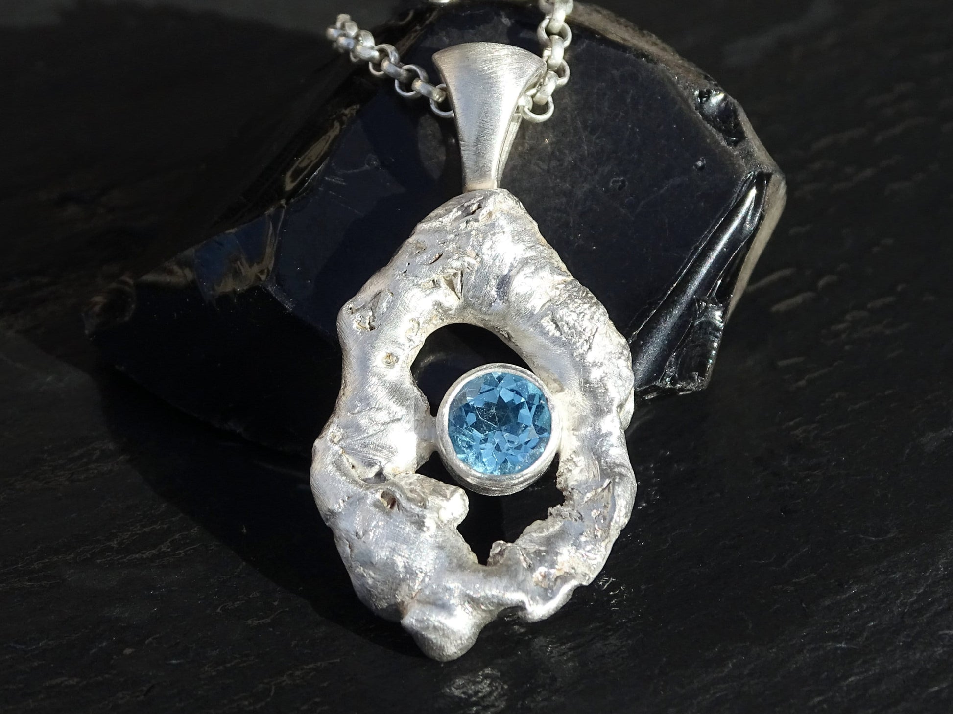 Sterling silver molten frame pendant with round faceted blue topaz gemstone on a silver chain