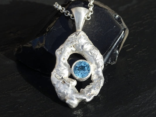 Sterling silver molten frame pendant with round faceted blue topaz gemstone on a silver chain