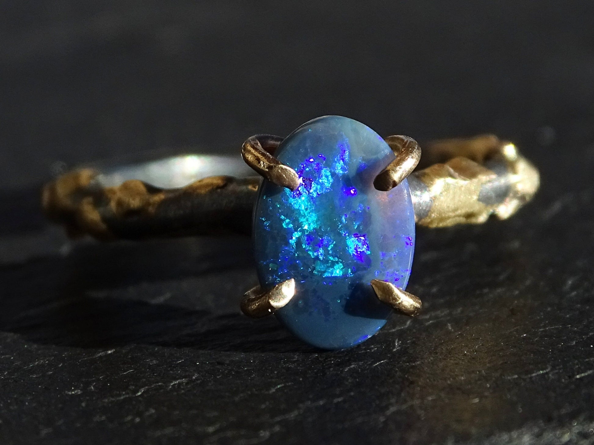 black Australian opal ring with blue and purple fire in 14k gold and black silver setting