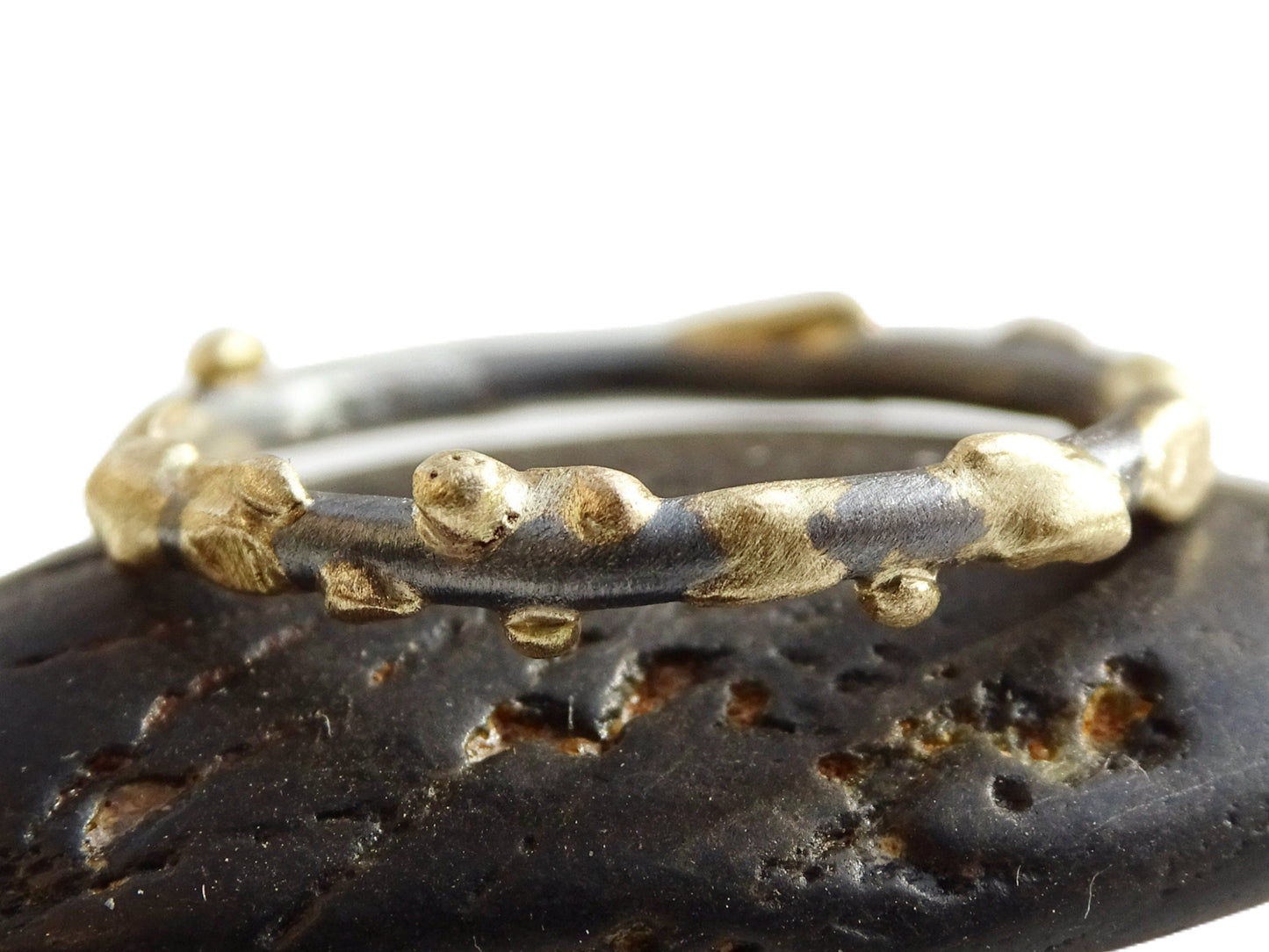 Close-up of a unique Viking style silver gold stacking ring with 14k yellow gold accents on a 2.0mm sterling silver band