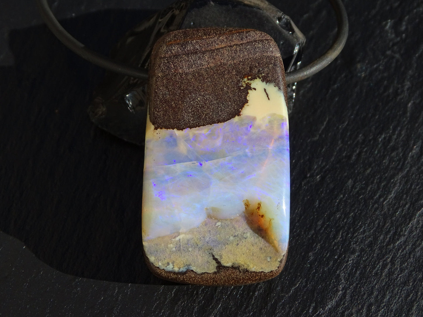 Large Australian Boulder opal necklace pendant with purple play of color on a black neoprene cord with sterling silver clasp