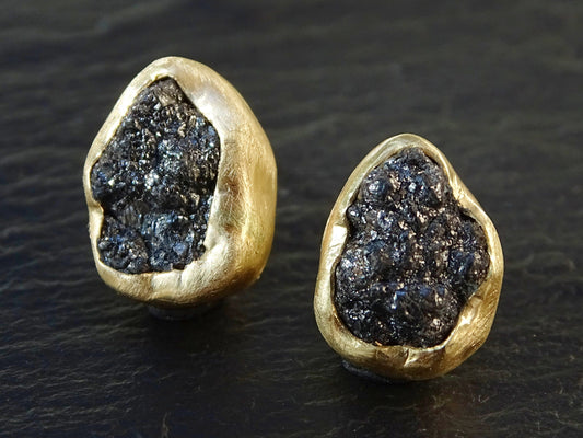 Raw black diamond stud earrings set in 14k yellow gold bezel settings.